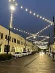 Calle del Distrito Bottleworks iluminada con luces de fiesta al atardecer