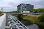 Vista panorámica de Kirkstall Forge con el edificio moderno junto al canal y puente peatonal