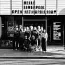 Grupo de personas frente a la entrada de Rough Trade Liverpool con letrero de inauguración