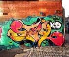 Mural de graffiti vibrante en pared de ladrillo con estilo artístico callejero