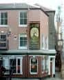 Vista exterior del pub Walnut Tree Shades con fachada rosa y cartel tradicional