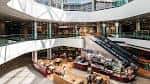 Vista interior del centro comercial con múltiples niveles, escaleras mecánicas y zona de comida