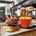 Plato de comida servido en el interior del pub: hamburguesa y patatas fritas con una cerveza