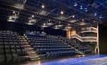 Interior del auditorio con butacas y escenario iluminado