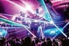 Interior del club con luces de neón y multitud bailando