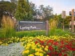 Señal de entrada a Loring Park rodeada de flores y vegetación
