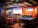 Interior del Bierkeller Liverpool con mesa de billar y pantallas para eventos deportivos