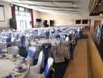 Sala de eventos preparada con mesas redondas y sillas decoradas para una celebración