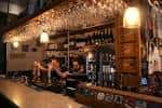 Barra interior con copas colgantes y personal atendiendo clientes