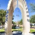 Arco blanco con banderas al fondo bajo cielo azul