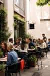 Terraza exterior del The Anthologist con invitados disfrutando de bebidas y conversación en ambiente relajado