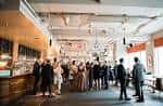 Evento corporativo en el espacio central del venue con asistentes en pie junto a barras de catering y decoración minimalista