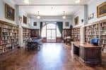 Interior de la biblioteca histórica con estanterías llenas de libros y mobiliario clásico