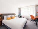 Habitación estándar del hotel con cama doble, escritorio y ventana con cortinas claras