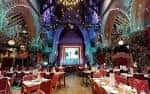 Interior decorado para evento navideño con mesas dispuestas y luces festivas en el techo abovedado