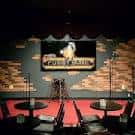 Escenario del Funny Bone Comedy Club con decoración de ladrillo y mesas para audiencia