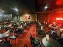 Interior amplio del club de comedia con iluminación roja y disposición de mesas