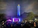 Evento nocturno en River Tower Park con iluminación de la torre y público reunido
