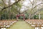 Ceremonia al aire libre bajo árboles con arcos decorativos