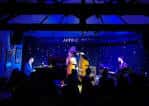 Concierto en vivo en el interior del Toulouse Lautrec con músicos en escena bajo luces azules