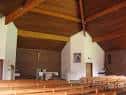Interior de la iglesia con vigas de madera y altar central
