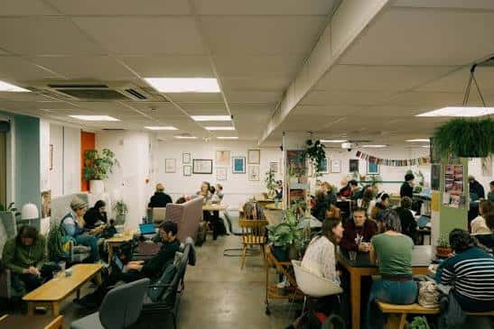 Interior del espacio comunitario Common Ground con personas sentadas en mesas y sofás