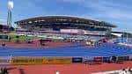 Vista panorámica del Alexander Stadium con pista de atletismo azul y gradas bajo cielo despejado