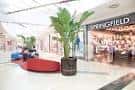 Interior del centro comercial con zona de descanso, plantas decorativas y tienda Springfield
