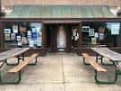 Entrada exterior del CBGB en St. Louis con mesas de picnic y cartelera de eventos
