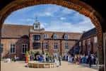 Evento al aire libre en el patio de Fulham Palace visto desde un arco de ladrillo