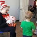 Voluntaria disfrazada del Gato en el Sombrero interactuando con un niño
