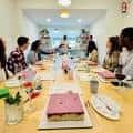 Interior del estudio mostrando una clase de arte con participantes sentados en mesas
