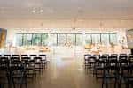 Vista interior del salón de eventos con mesas redondas y sillas blancas