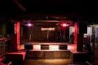 Escenario del venue con iluminación roja y equipo de sonido
