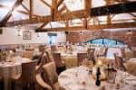 Salón de eventos interior con vigas de madera expuestas y mesas dispuestas para boda o celebración