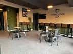 Interior del pub con mesas, sillas y barra en ambiente moderno