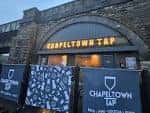 Vista exterior del Chapeltown Tap con su letrero iluminado y vallas decorativas