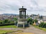 Monumento a Nelson en primer plano con vista urbana de Edimburgo al fondo