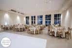Salón interior preparado para evento con mesas redondas y sillas doradas