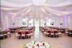 Gran salón decorado con telas blancas colgantes y mesas con manteles rojos
