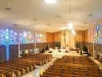 Nave principal de la iglesia con bancos de madera y vitrales iluminados