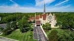Vista aérea de la fachada principal de la iglesia con su característica torre y jardines circundantes