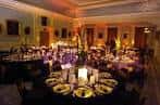 Salón decorado para una cena corporativa con mesas redondas y velas