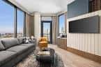 Interior de suite ejecutiva con sofá moderno, televisor y vistas panorámicas de la ciudad