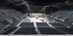 Interior del arena mostrando las gradas vacías y el escenario preparado para un evento