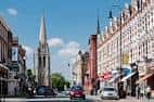 Vista de la calle principal en Muswell Hill con edificios históricos y una iglesia al fondo