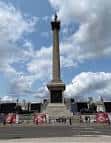 Primer plano del Monumento a Nelson con cielo nublado y banderas rojas en la base