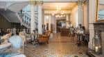 Hall principal con columnas clásicas, escalera y zona de recepción