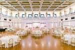 Gran salón del museo decorado para una boda con mesas redondas y iluminación elegante