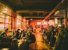 Interior del local con ambiente cálido y personas sentadas en mesas